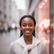 Smiling young African woman looking at the camera with a warm expression, in an urban setting.